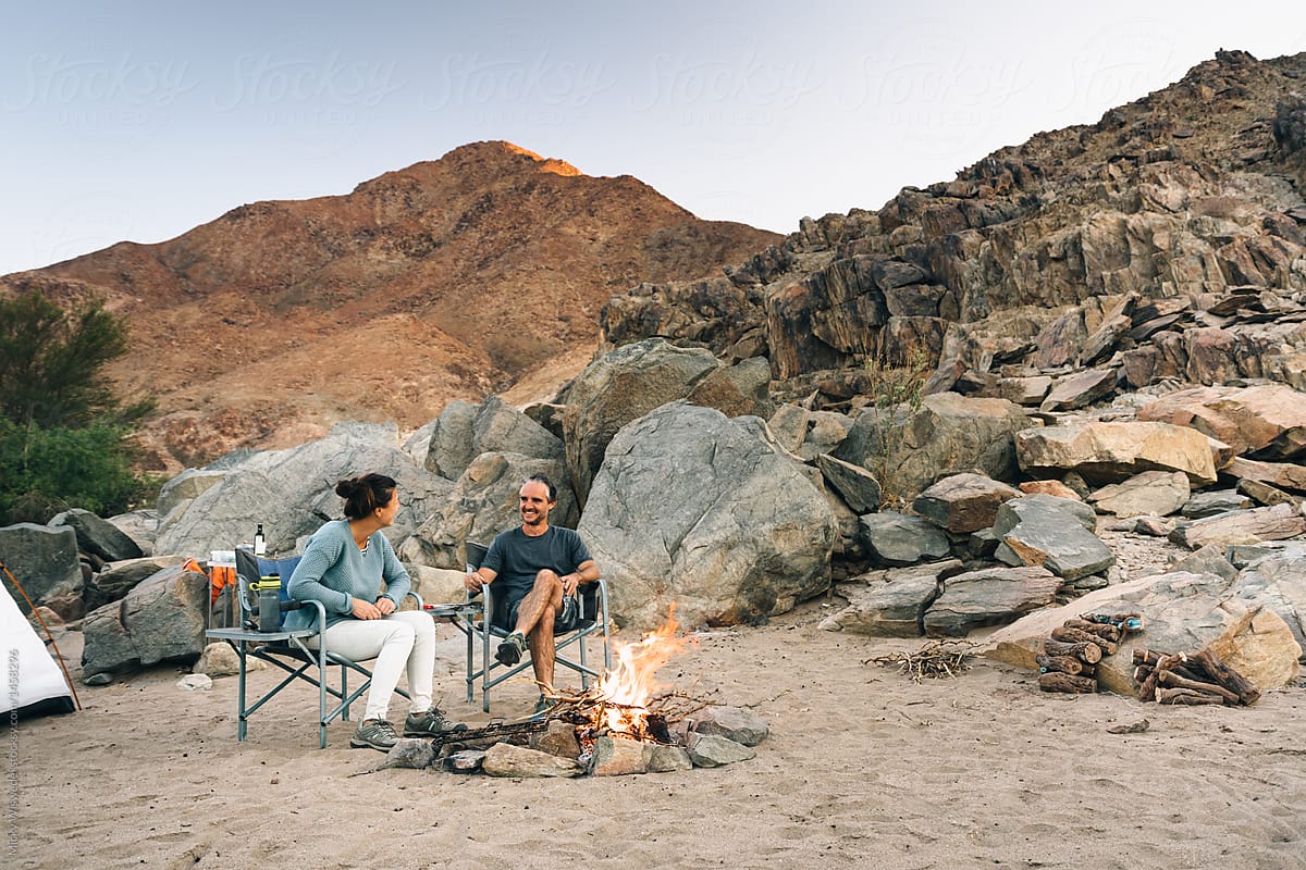 outdoors camping couple by campfire.