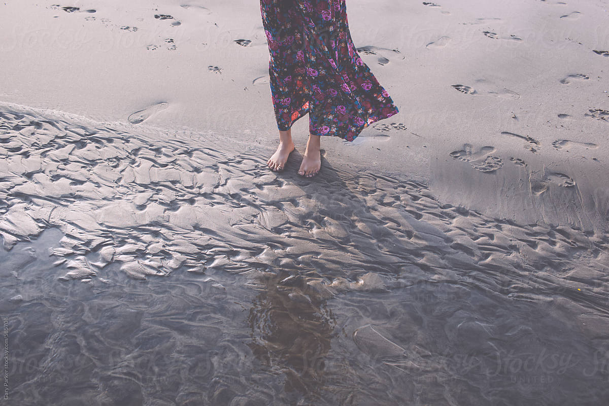 A girl standing on the wet sand on the beach