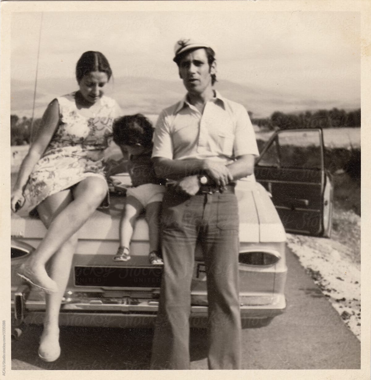 Old scanned photo of a family resting on the trunk of their car