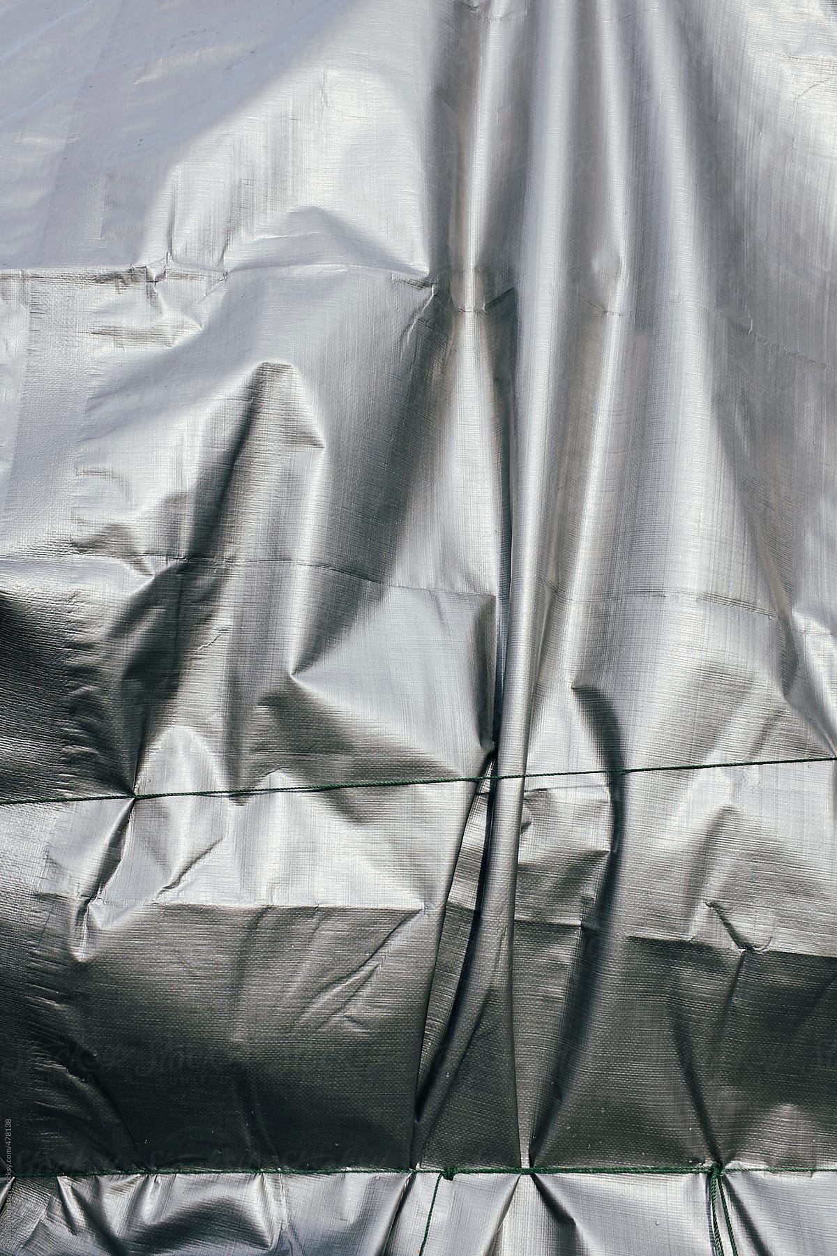 Closeup of silver tarpaulin covering pile of commercial fishing equipment