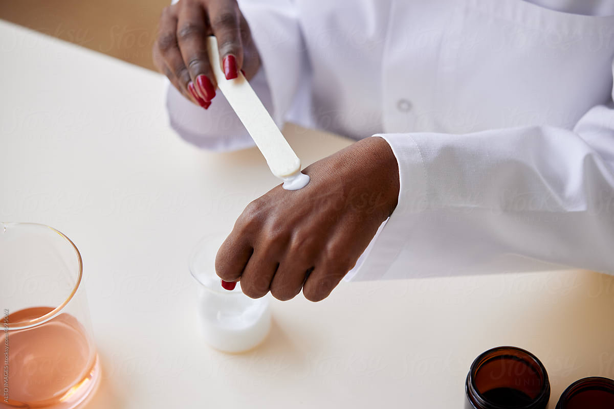 Faceless black pharmacist applying cream on hand