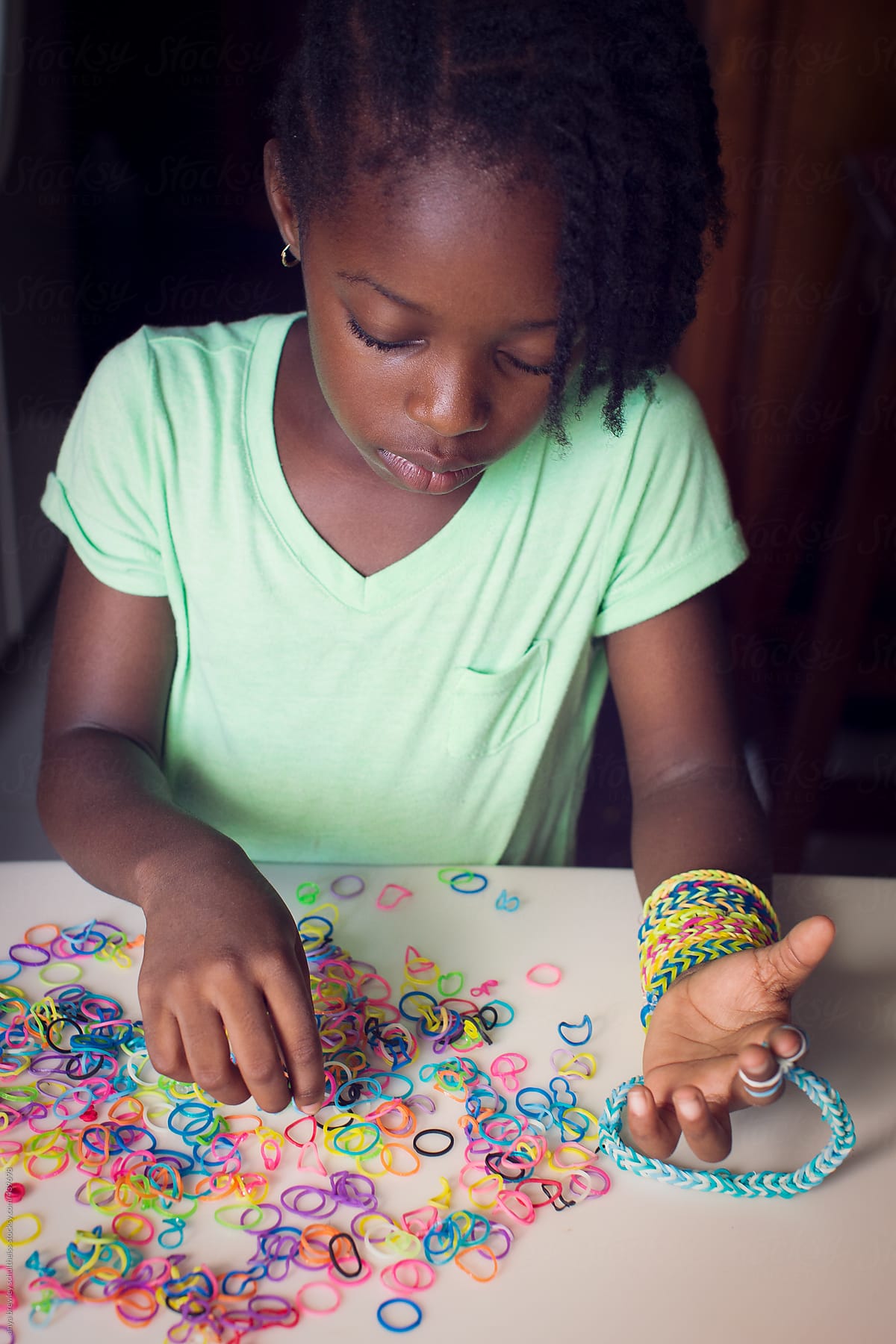 Young child creating a bracelet  with rubber bands