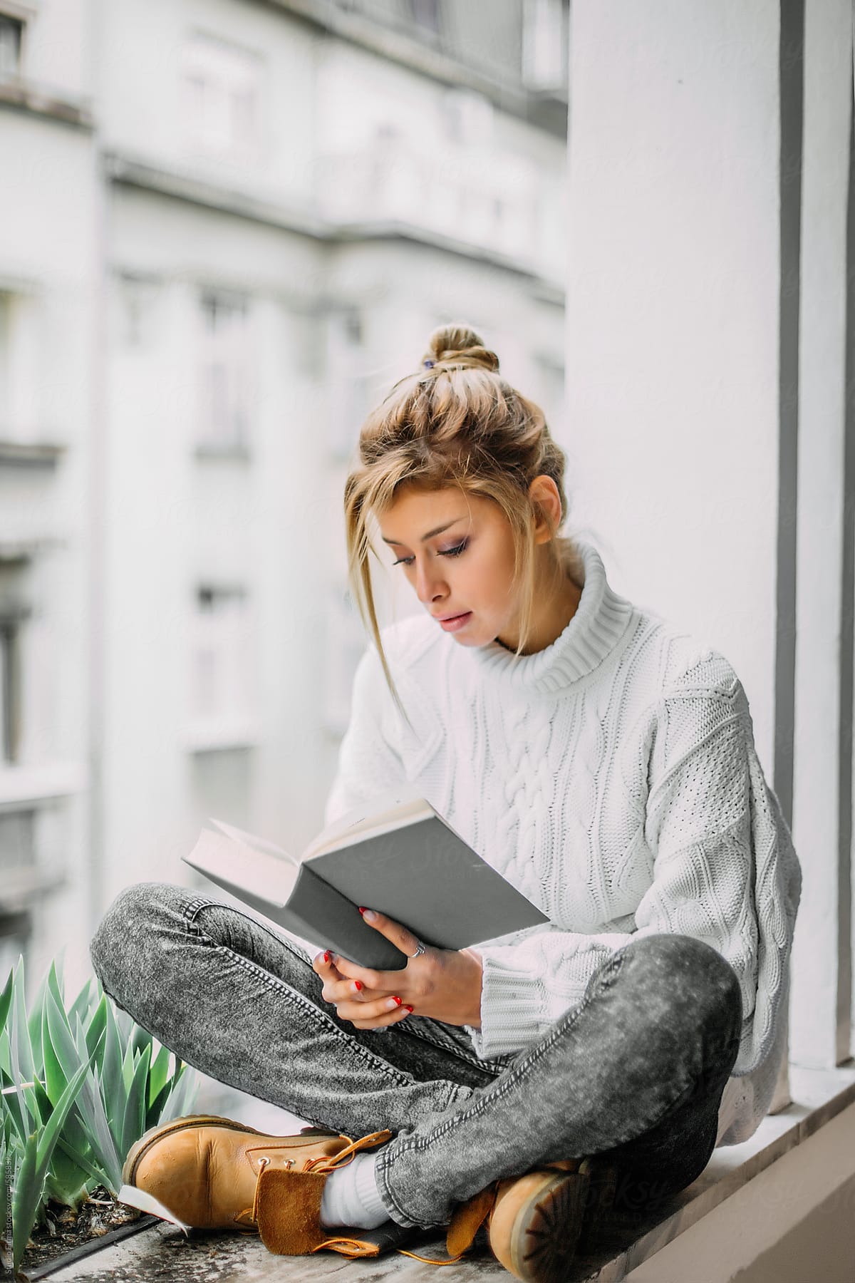 Beautiful Blonde Woman Reading A Book At Her Home Balcony By Stocksy