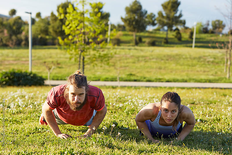 Determined Man And Woman Doing Push-Ups In Park