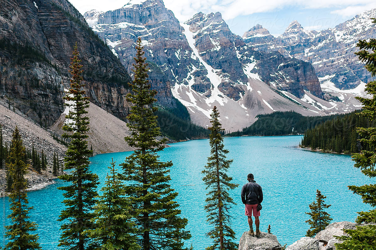 A man standing on a rock at Moraine Lake in Alberta, Canada