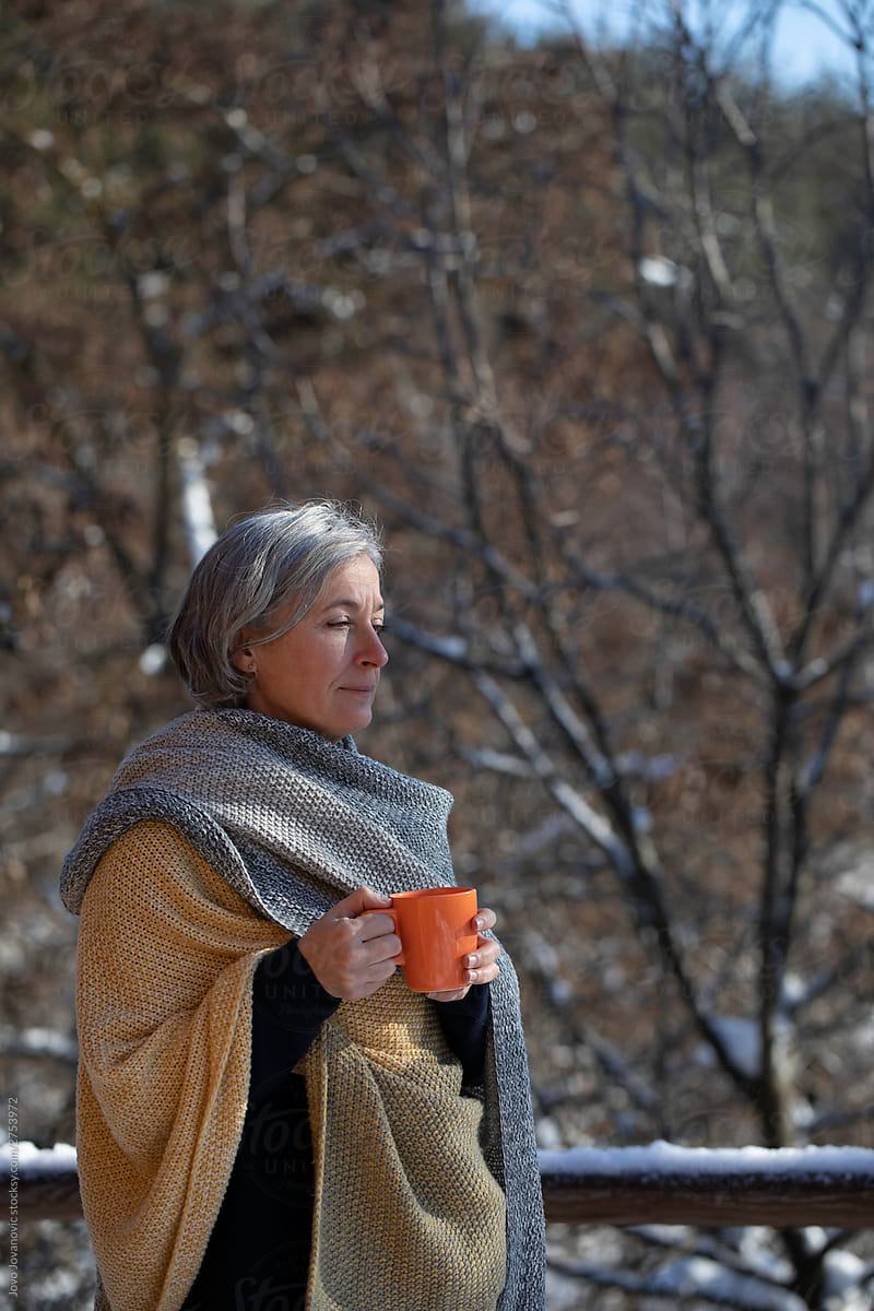 Older woman drinking hot tea outside in winter