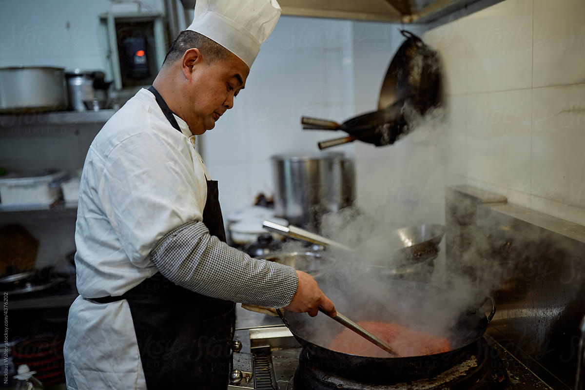 Chinese chef prepares sauce in a restaurant kitchen