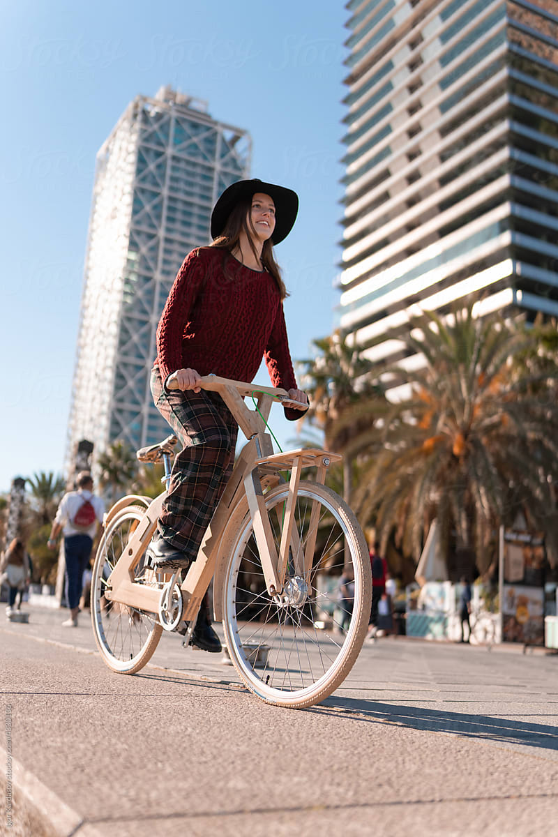 Optimistic female cyclist riding wooden bike on street