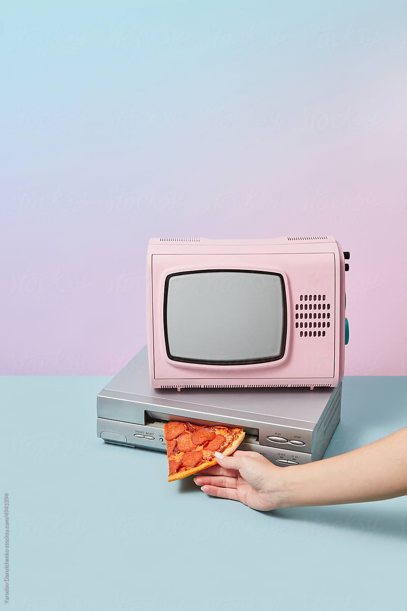 Retro TV and pizza pushed in VCR player by hand.