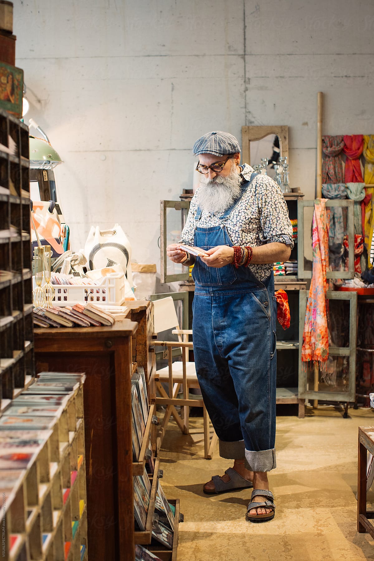 Indoor Portrait of Fashionable Elderly Hipster With Grey Beard Looking at Artisan Notebook
