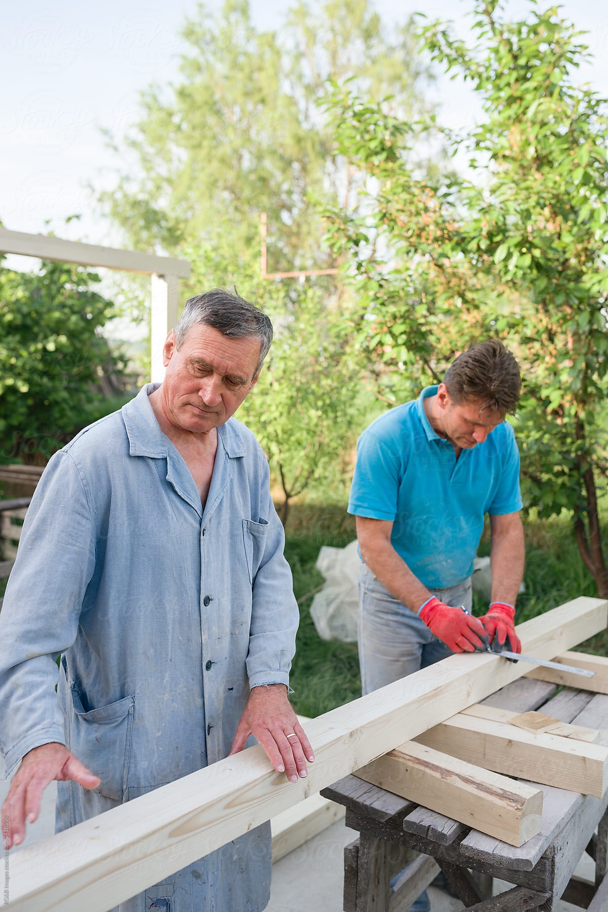 Male carpenters taking measurements of wooden plank outdoor
