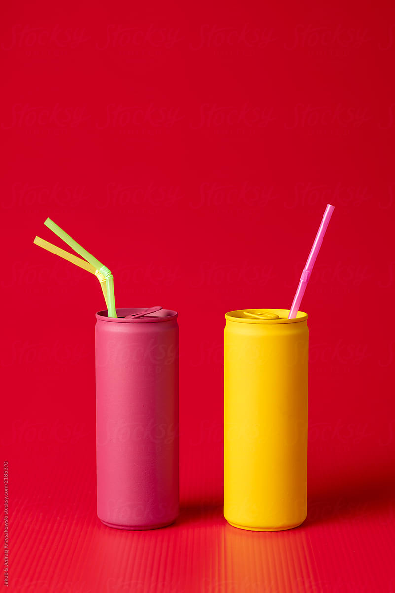 Yellow and pink cans with a straws on red background