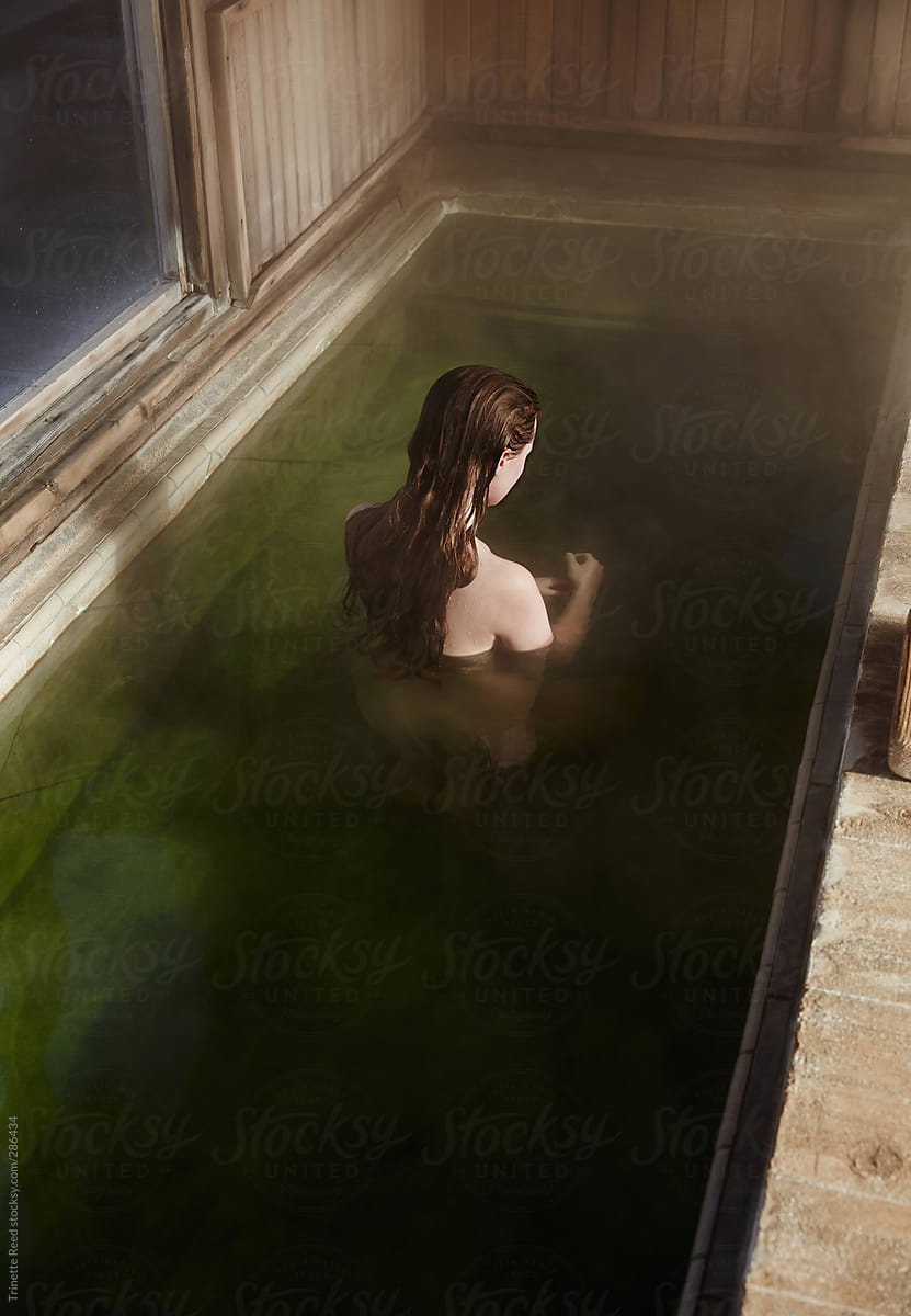 Woman relaxing in Japanese hot springs hot tub pool at spa