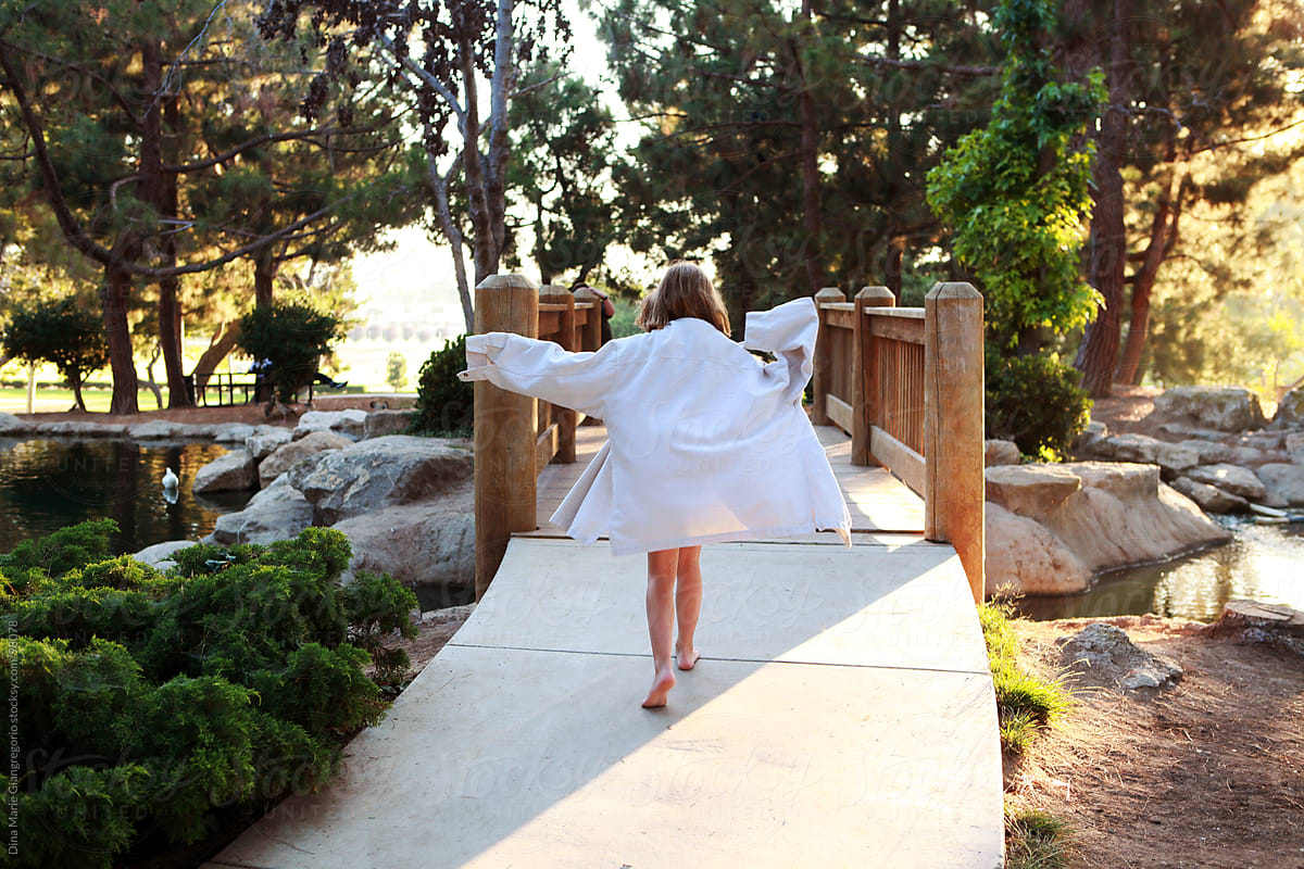 Little girl walking towards bridge wearing oversized white shirt