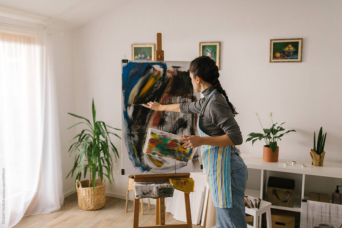 Woman artist painting on canvas in art studio