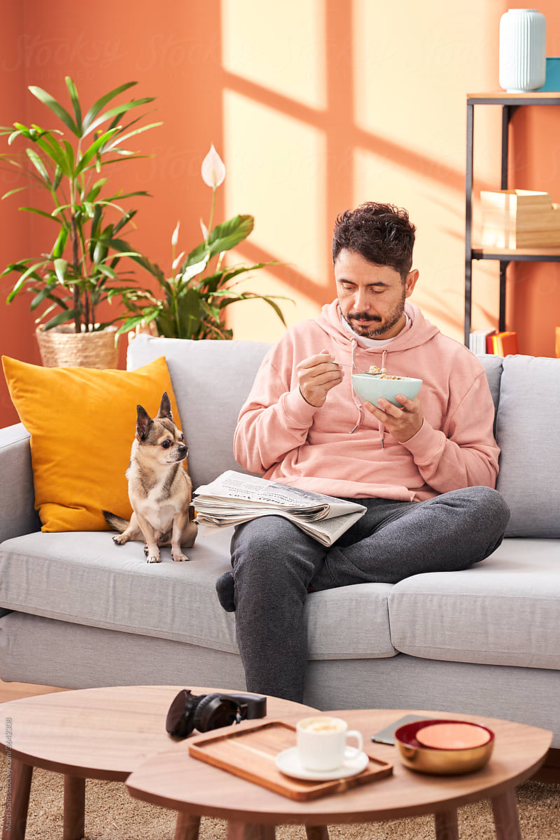 Man with newspaper and dog enjoying breakfast at home