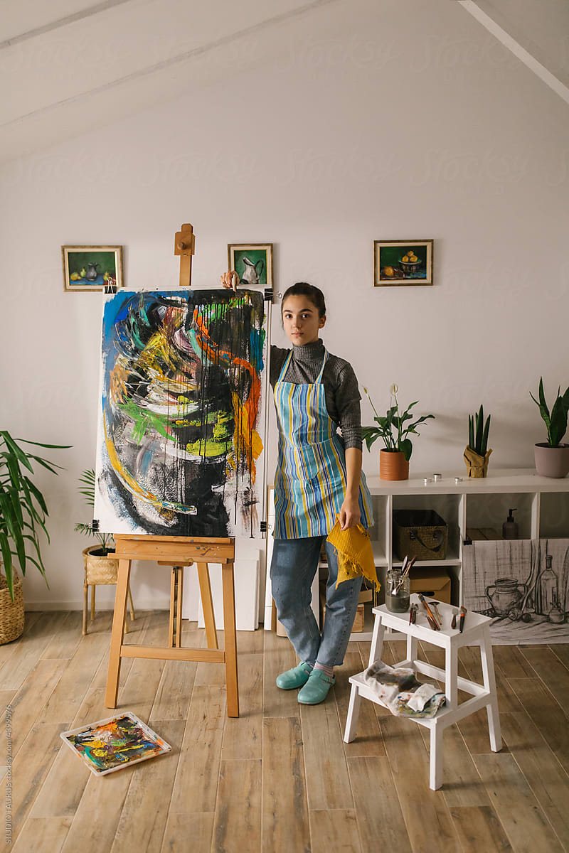 Portrait of young artist posing with her painting