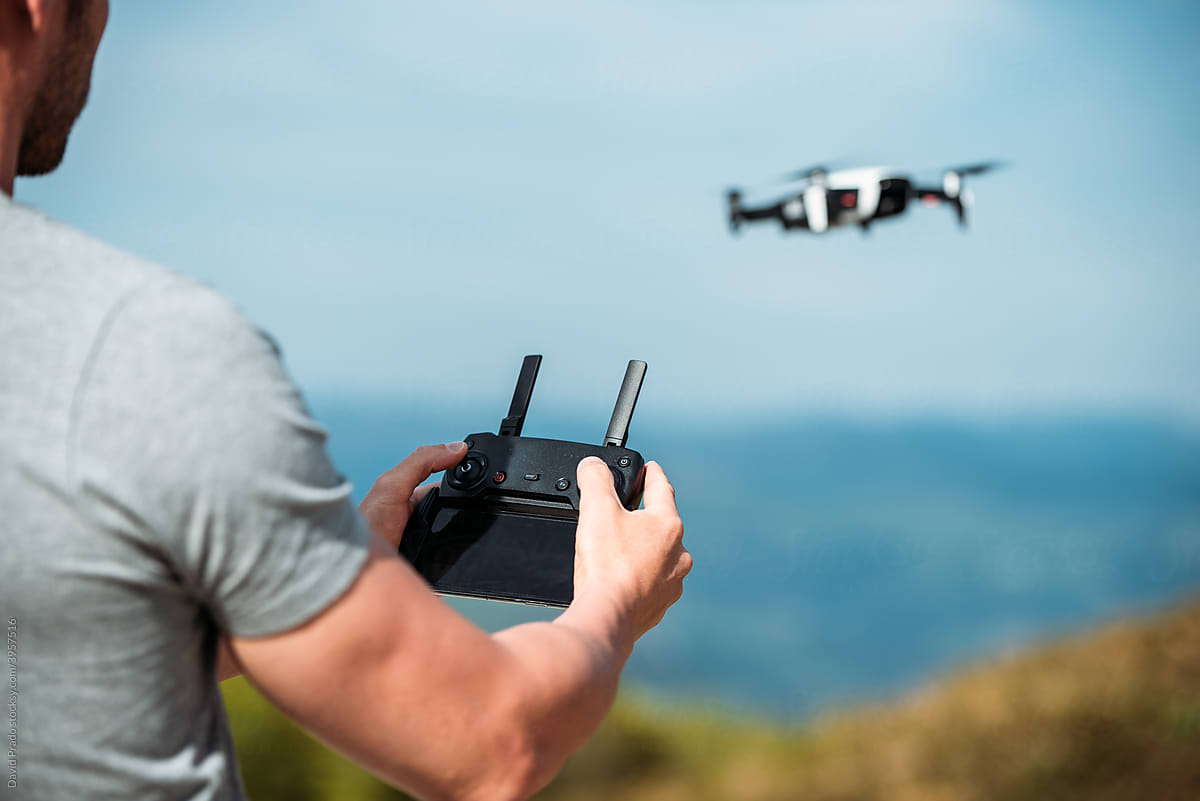 Man controlling flight of drone in hilly terrain