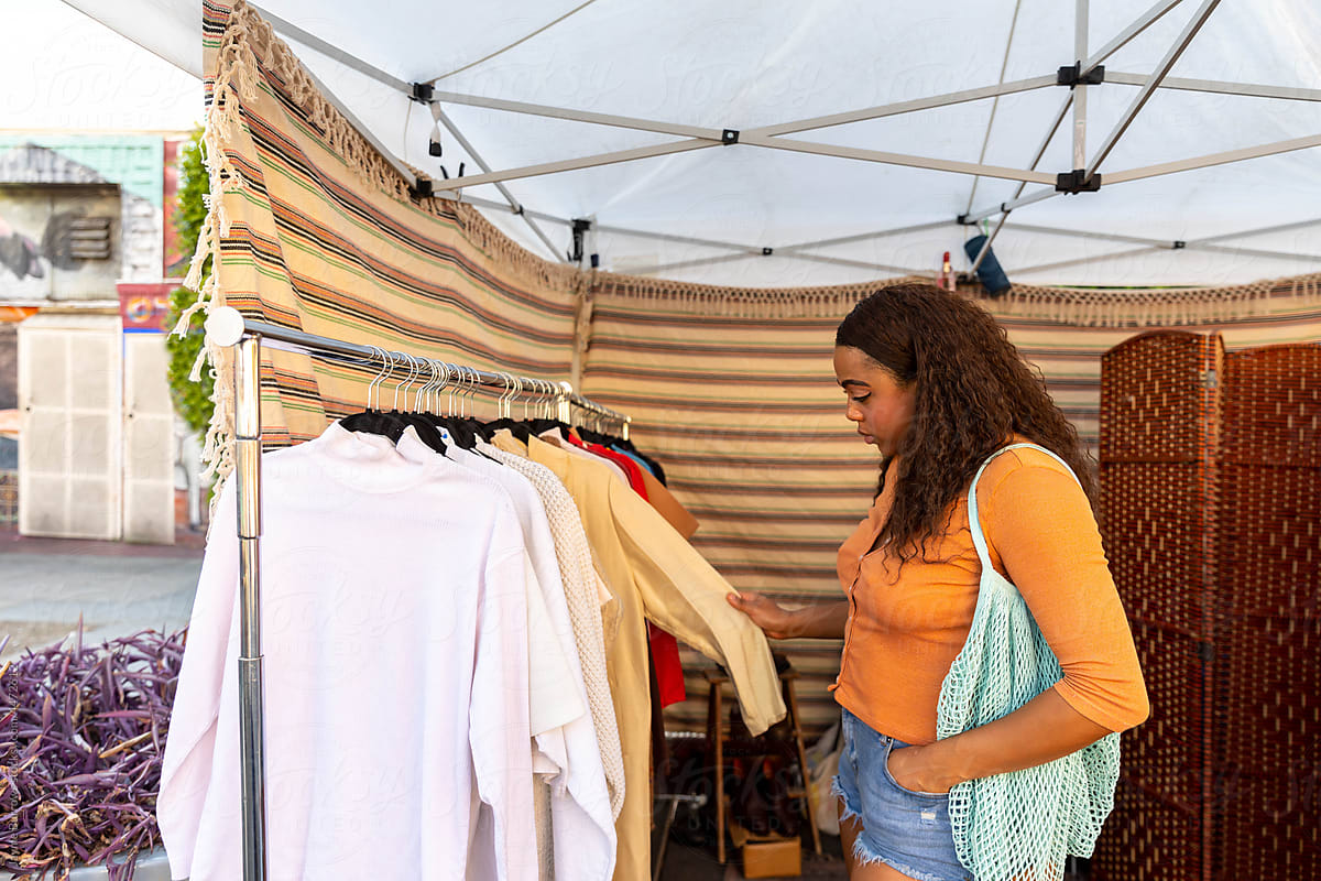 Woman Browses Clothing at Outdoor Market