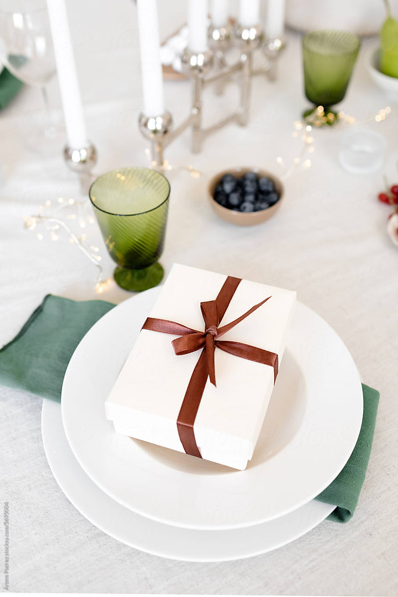On the decorated table there is a white box with a Christmas gift