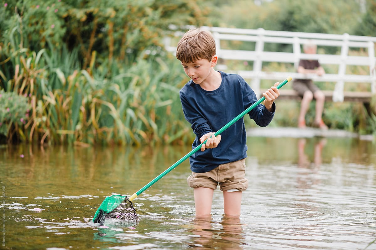 Child Trying To Catch Fish With A Fishing Net by Stocksy Contributor  Rebecca Spencer - Stocksy