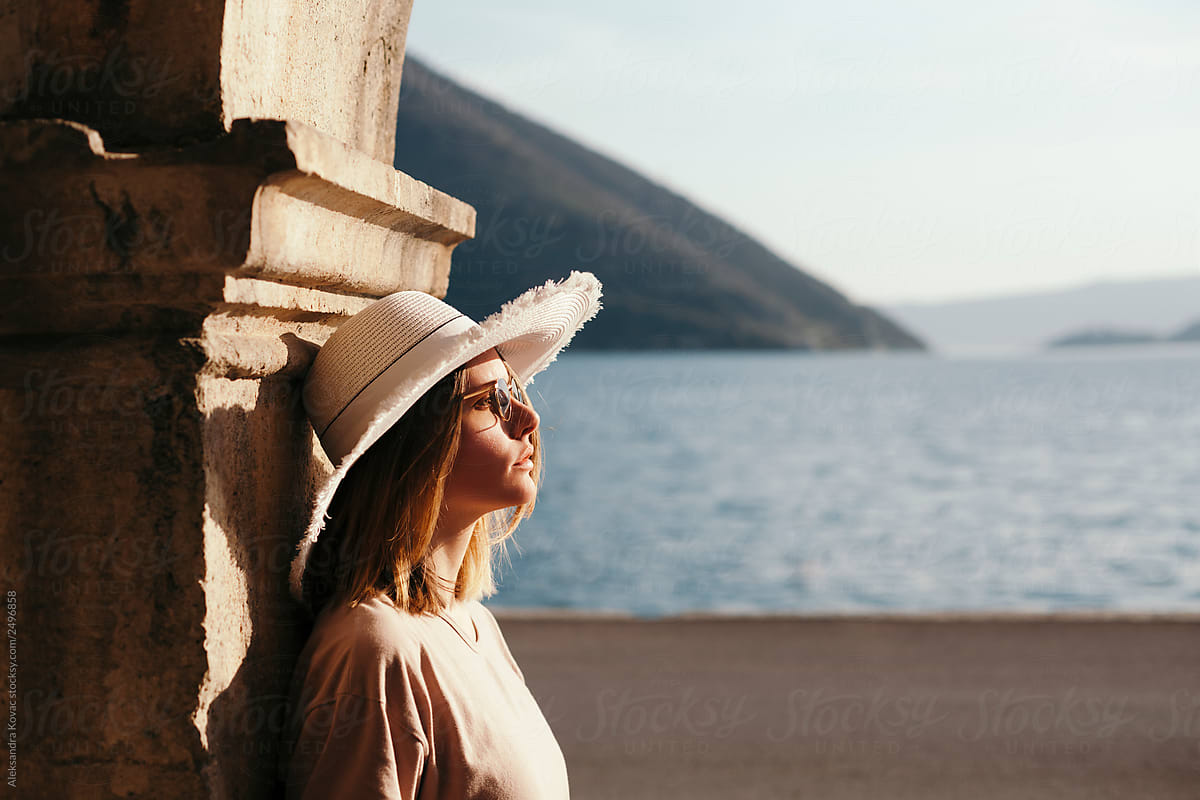 Woman in sun hat in the city by the sea