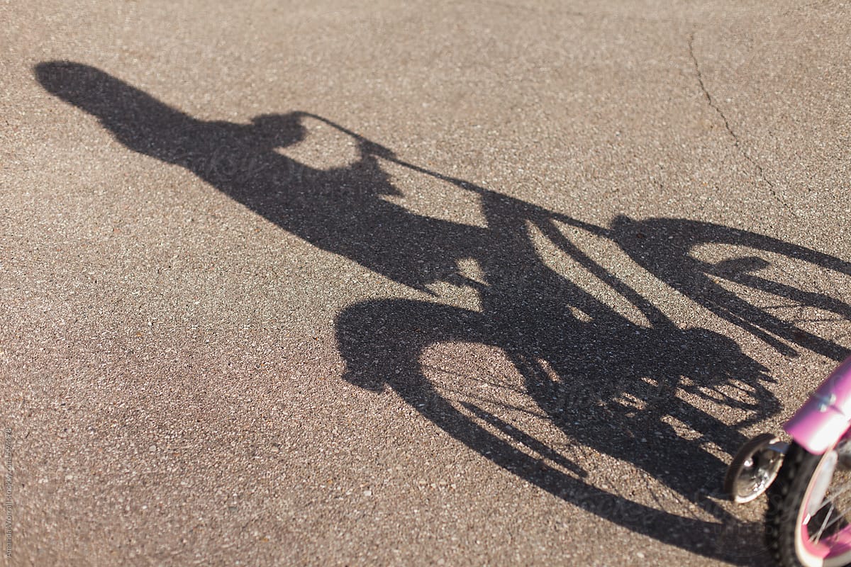 Diagonal shadow of a child riding a bicycle with training wheels