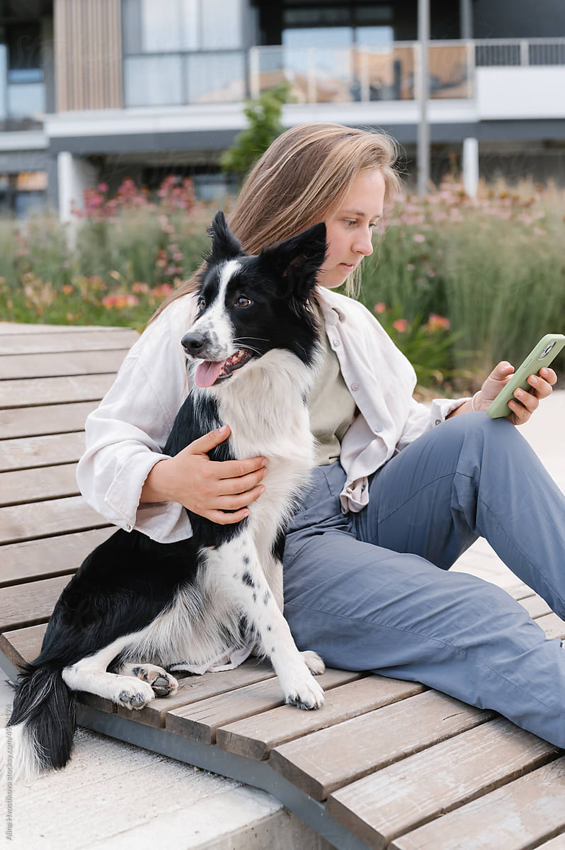 Woman with dog using smartphone in park