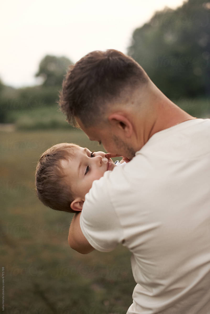 dad holds his son in his arms in nature