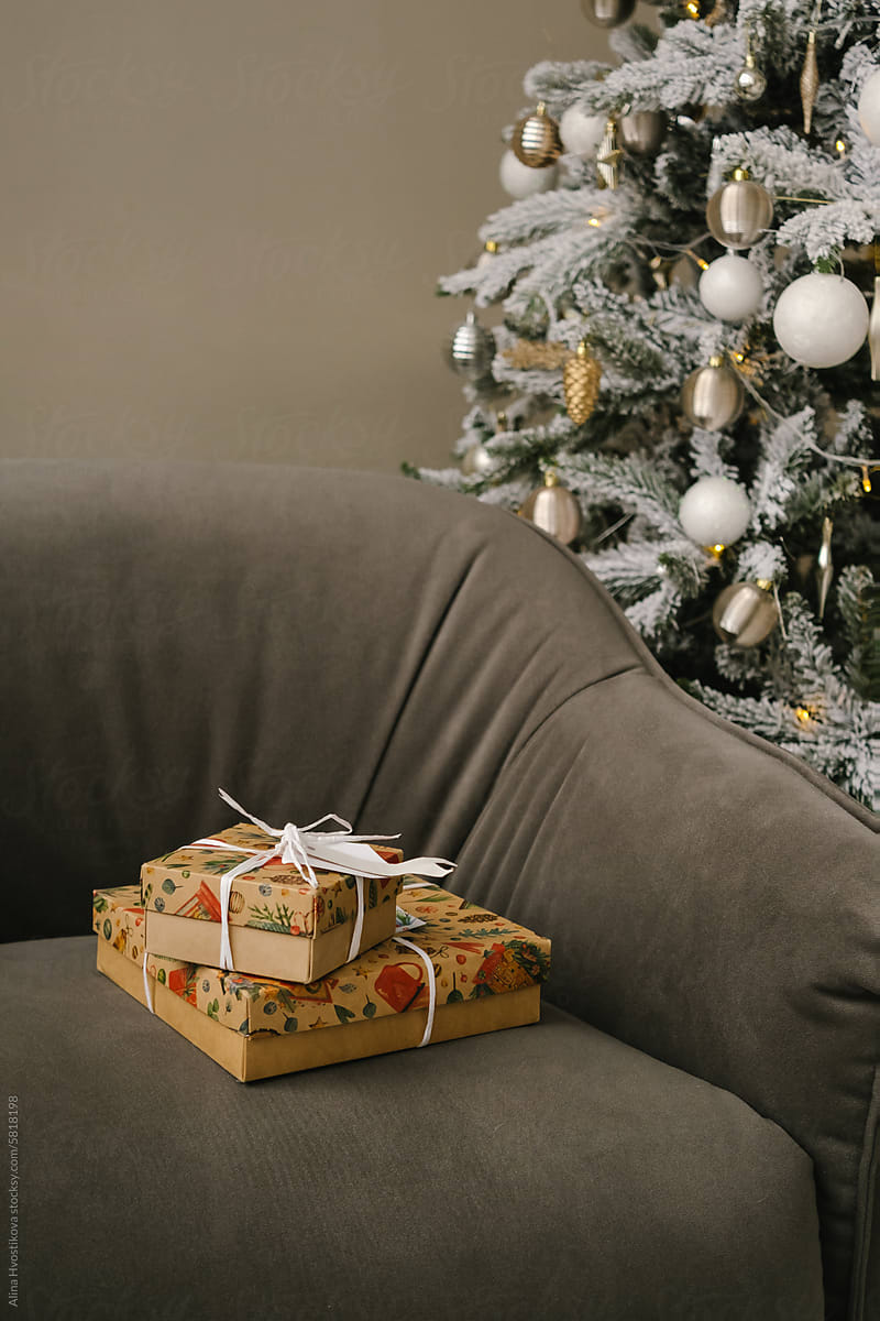 Christmas present boxes on armchair near Christmas tree