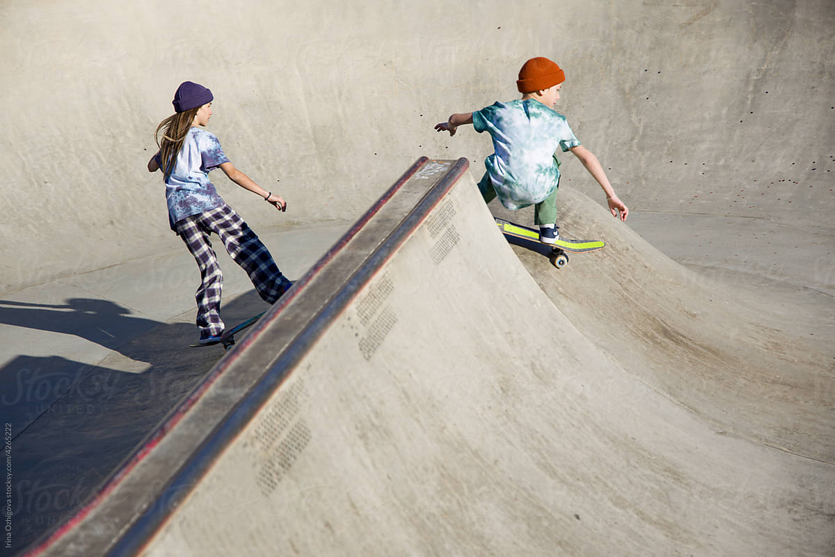 Teen skaters riding skateboards in bowl together