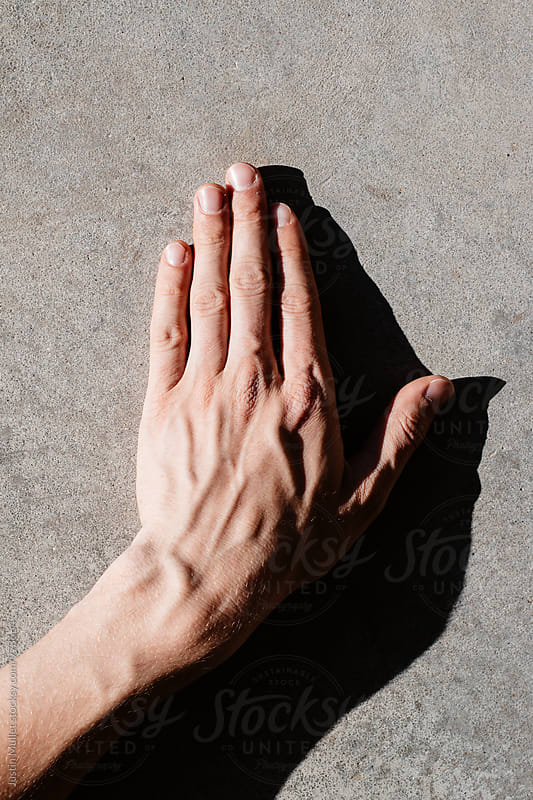 Man\'s left hand and wrist on laying on concrete