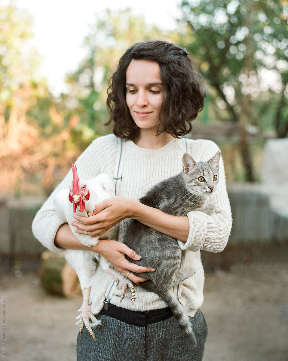 Young woman holding cat and chick