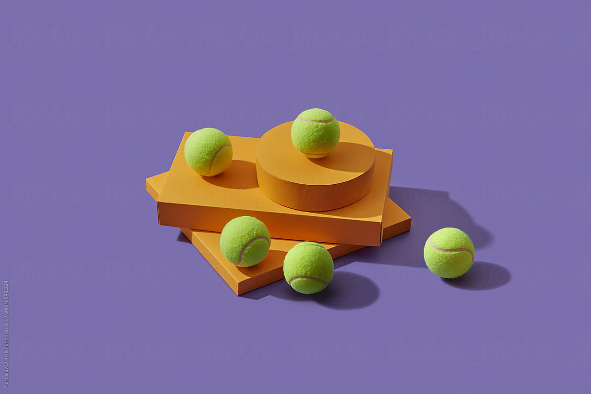 Five tennis balls placed on paper geometric shapes in studio