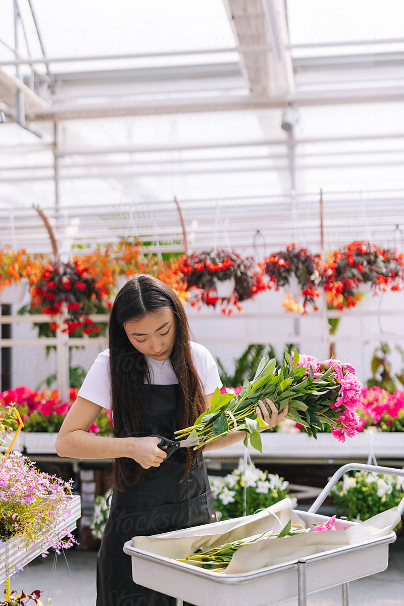 Woman pruning piece of flowers in store