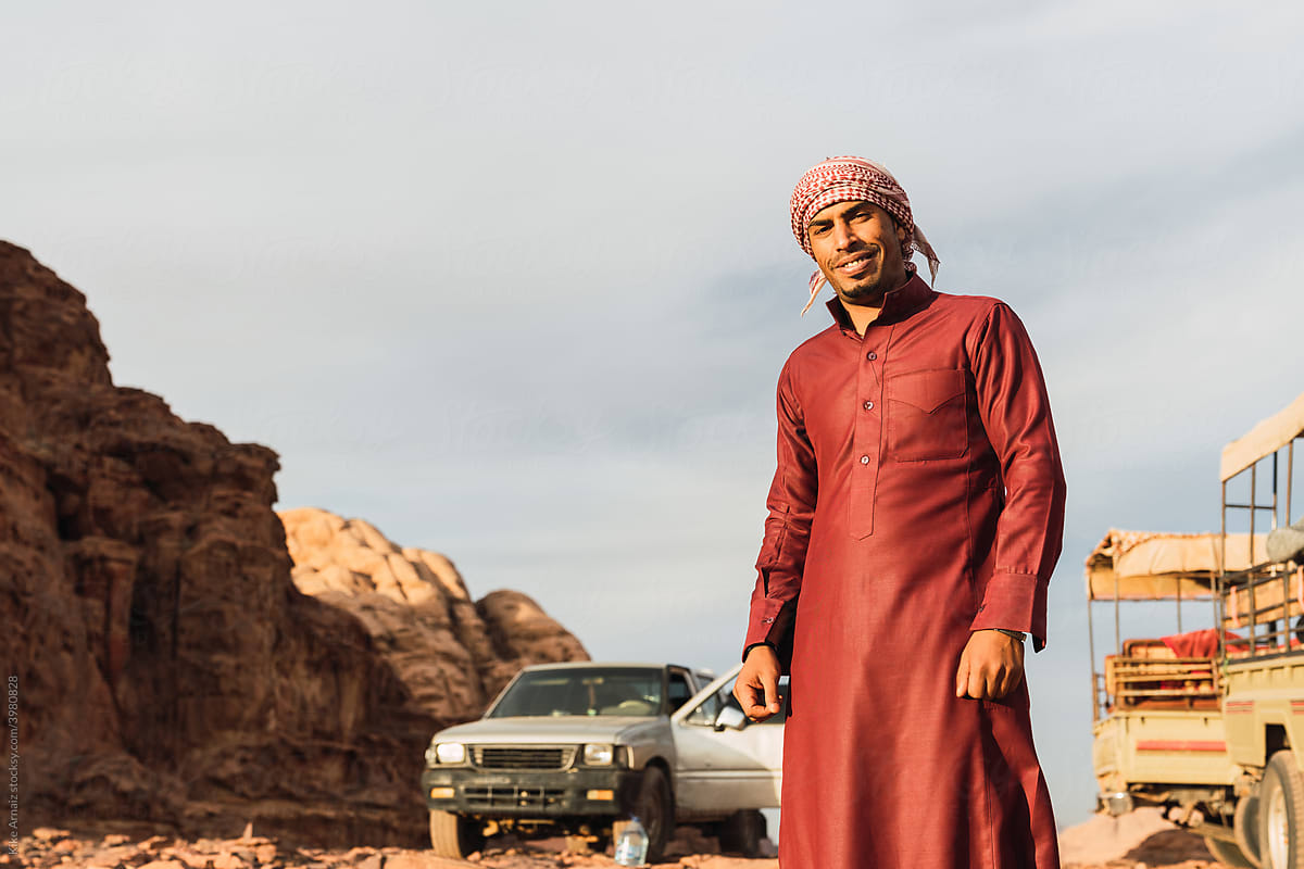 Smiling Arabic man near cars on mountain