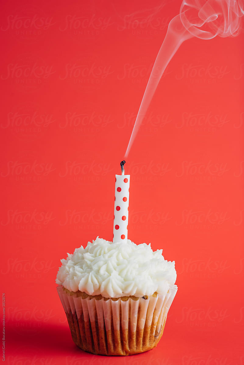 Birthday cupcake with smoking candle on a red background