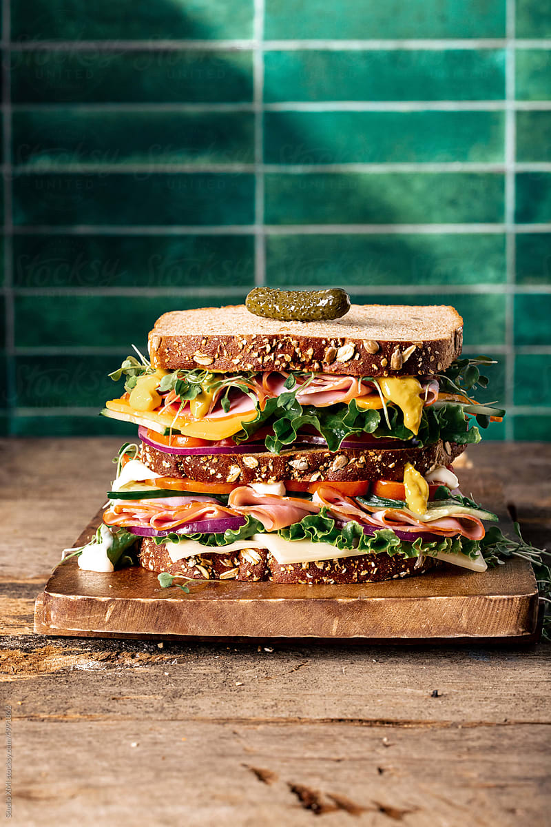 Sandwich on Wood Cutting Board with Green Tile Background