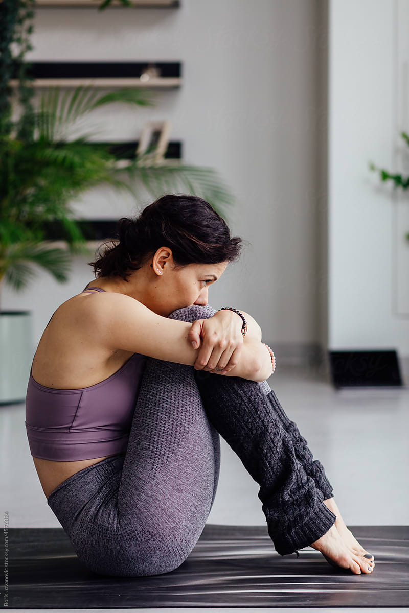 Woman sitting on a yoga mate