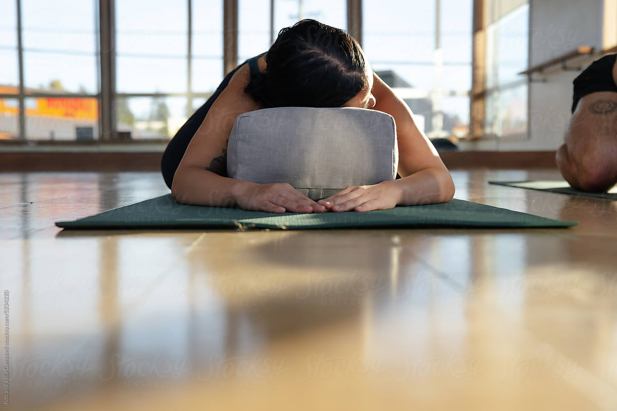 Woman in child\'s pose using yoga pillow.