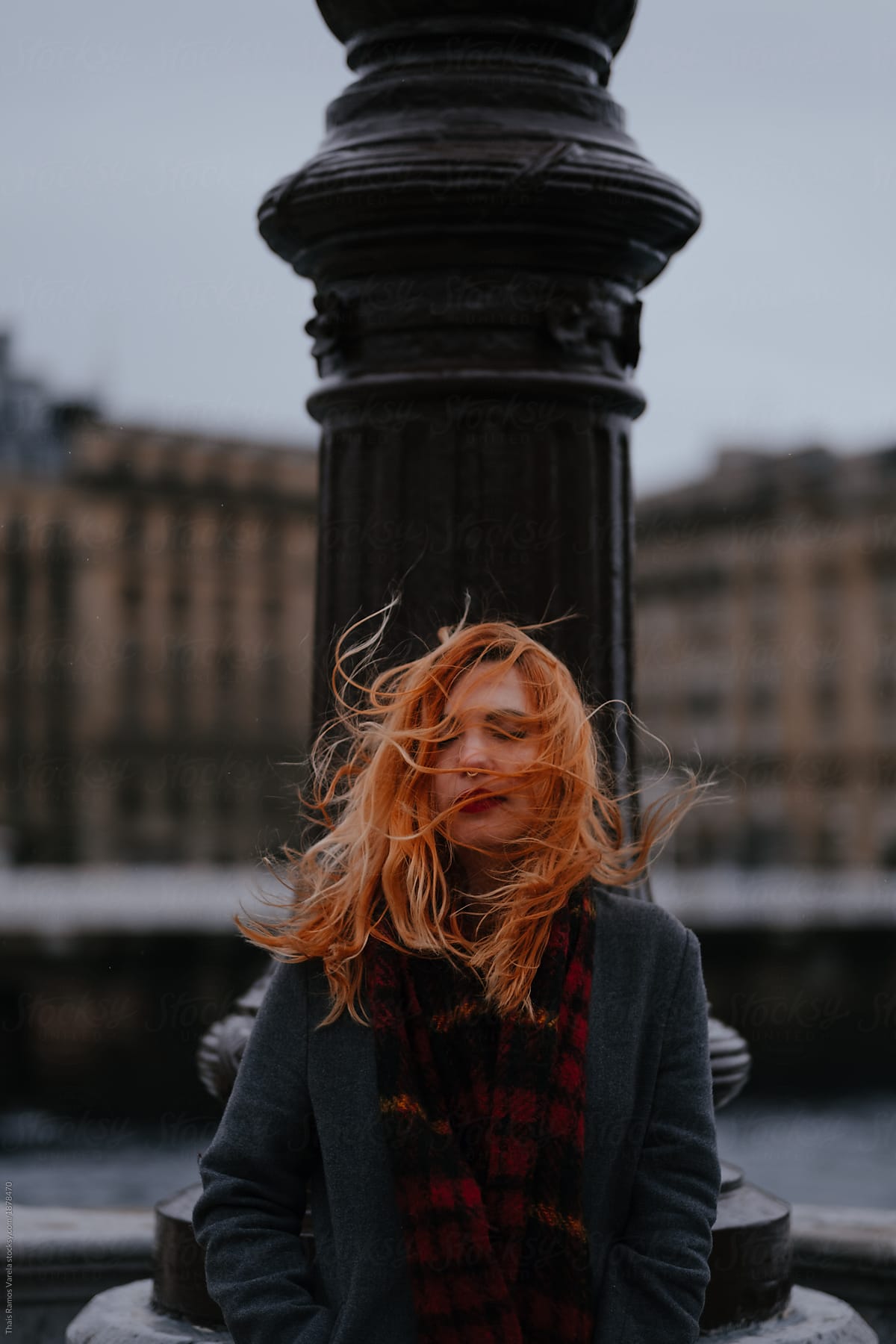 portrait of a woman with mess hair cause of te wind in a bridge over a river