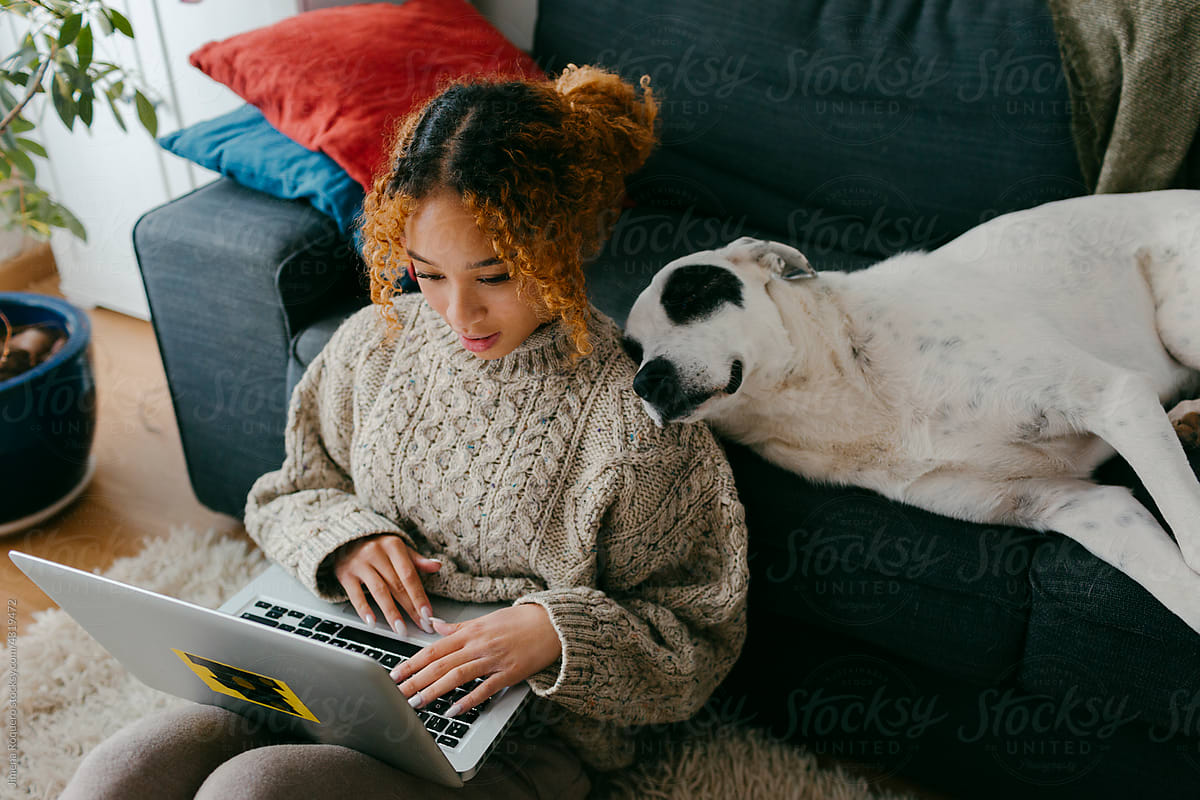 Teenager at home relaxing with dog while using laptop