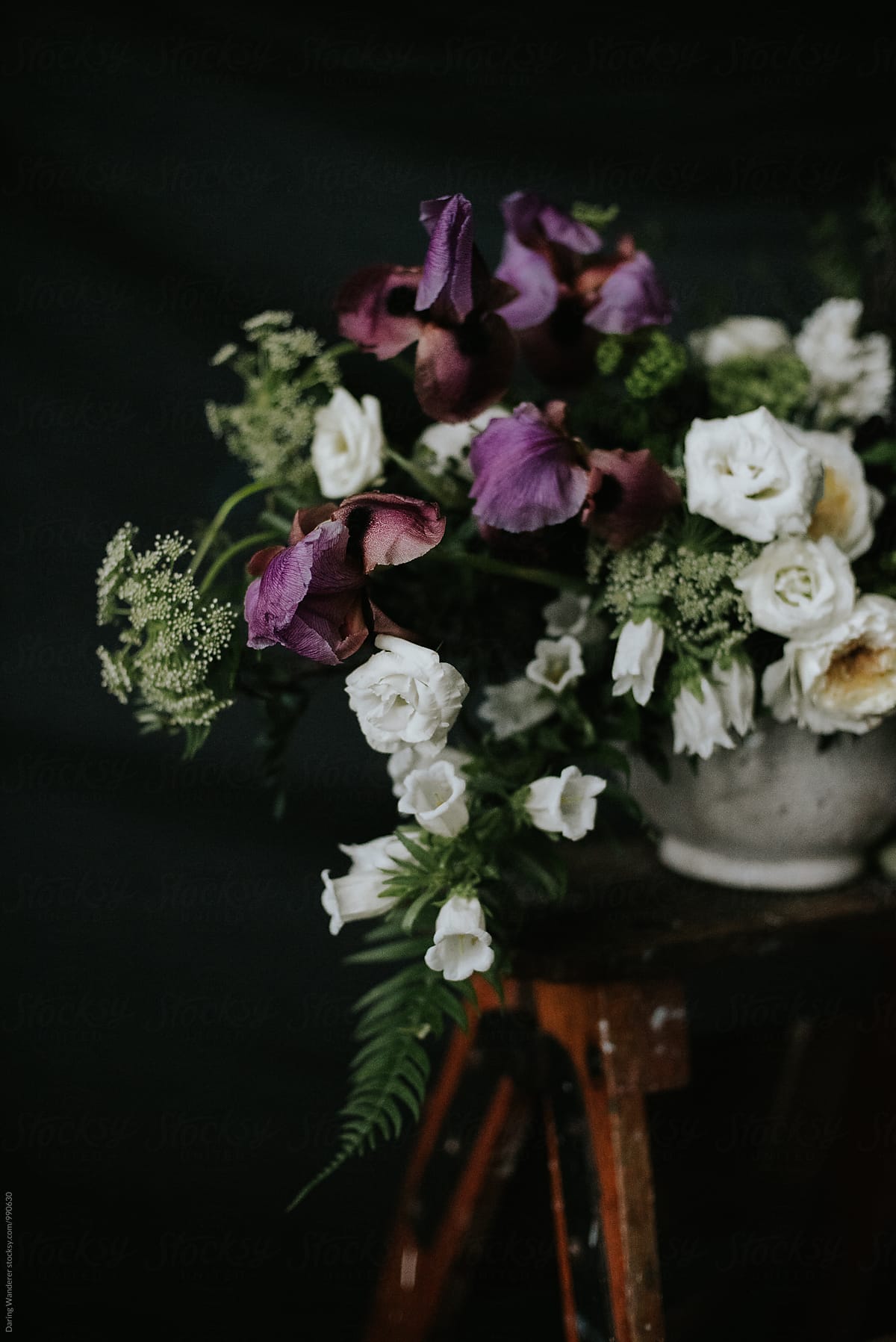 Dark and moody purple and white wedding flower arrangement with dark background