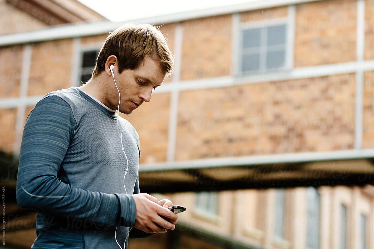 Male athlete with smart phone in urban environment