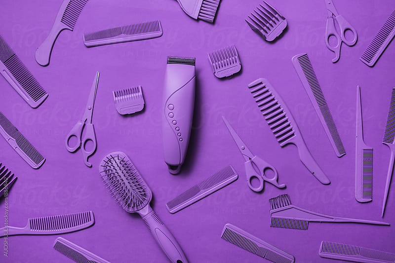 Various hairdresser tools in purple color on purple background.