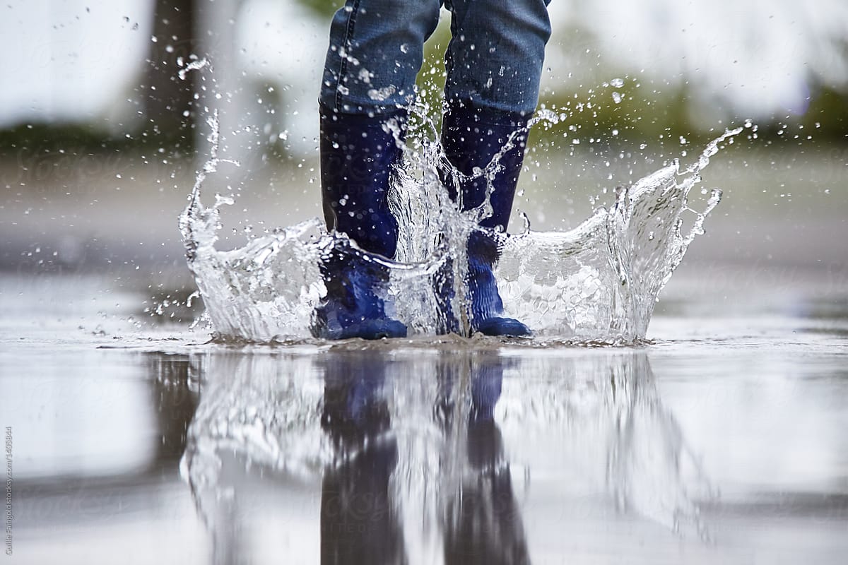 Jumping rubber boots in puddle.