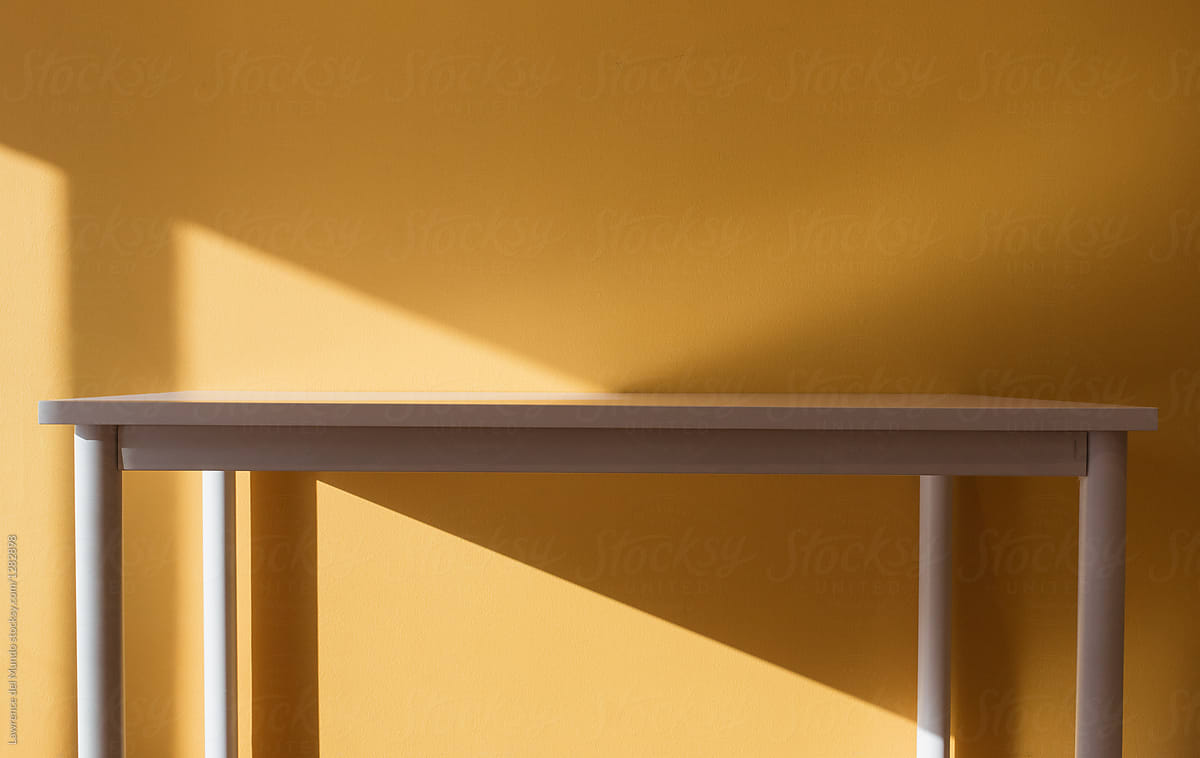Light, shadow, angle, triangle, yellow, and a table come together for a geometric display.