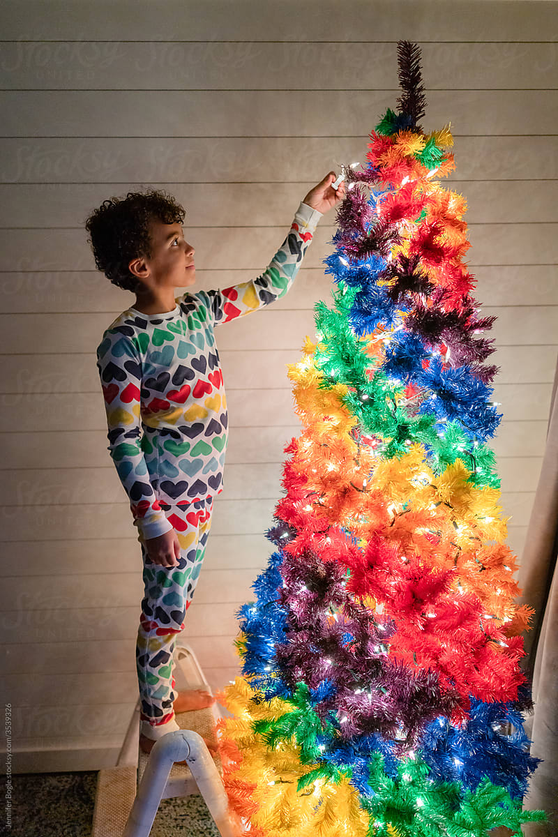 Girl adds final lights to rainbow Christmas Tree