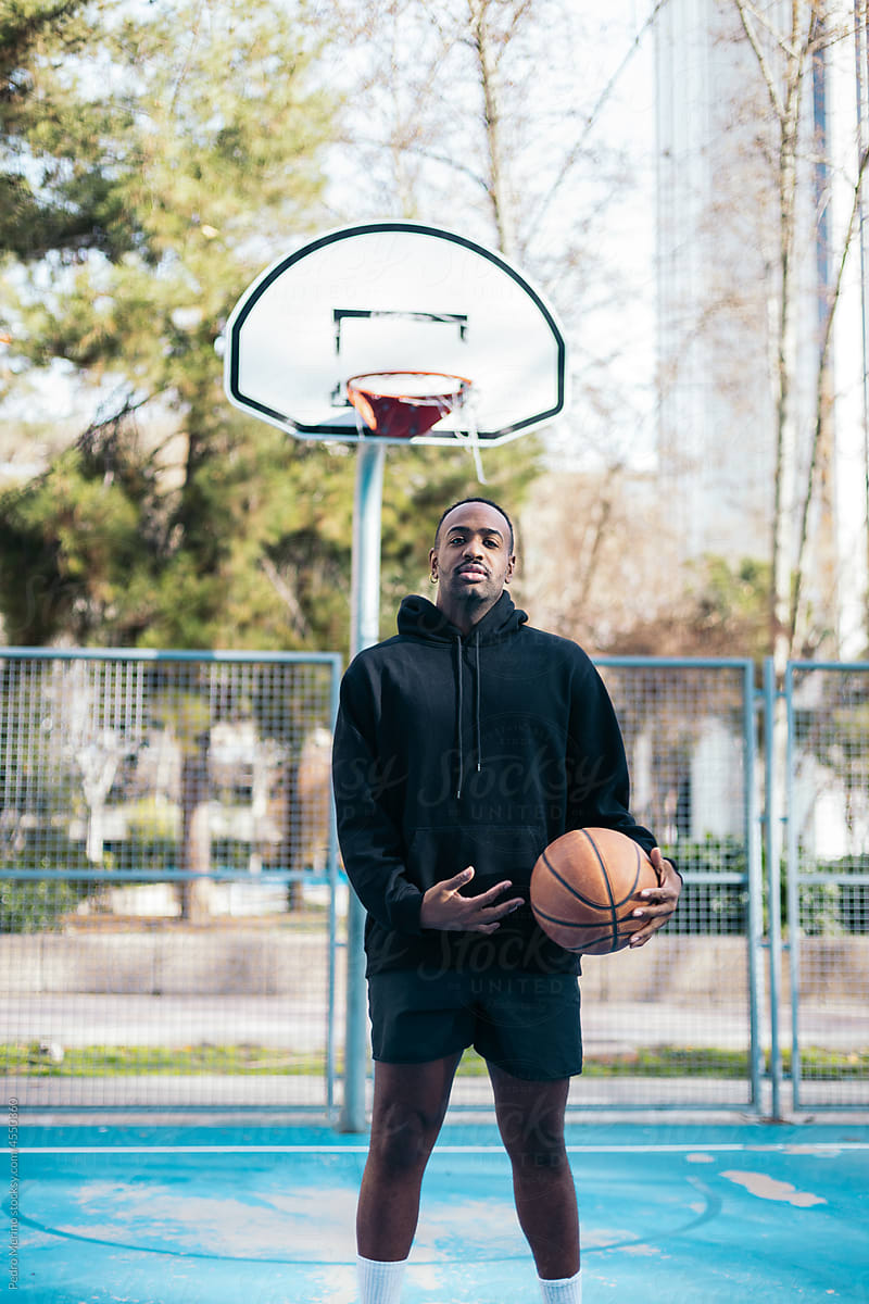 Young man holding basketball ball on a basketball court