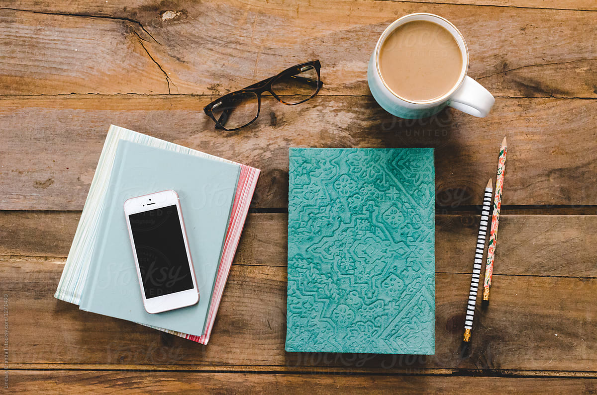 Table scene with glasses, coffee, notebooks, and a smart phone
